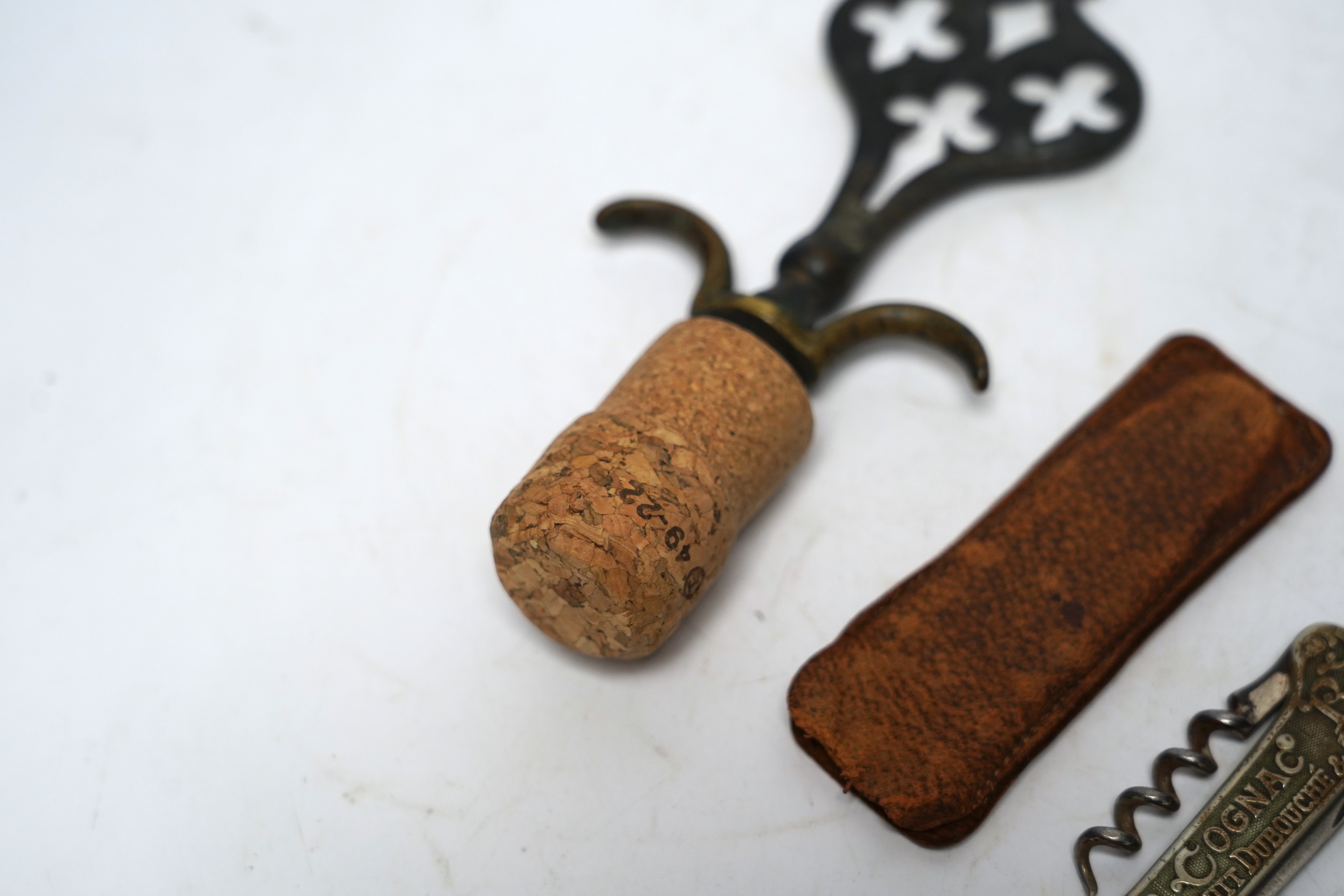 Two corkscrews; one advertising Jean E Sottiris-Le Caire, on reverse, Cognac Bisquit, Bisquit Du Bouche &Cie Cognac together with an ornate brass corkscrew largest 14cm